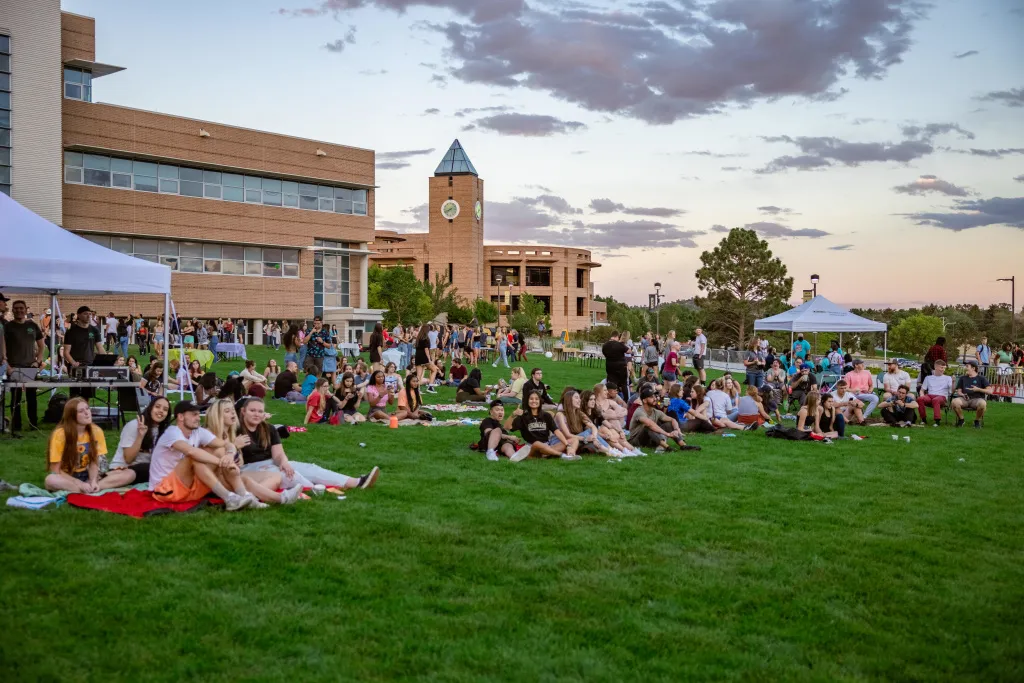 photo of students sitting on the west lawn on uccs campus for a concert